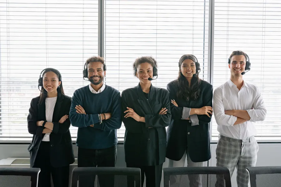 A team of five colleagues standing together, smiling with arms crossed